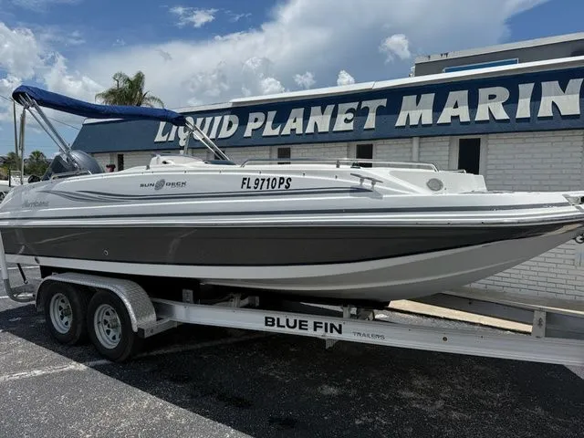 Slide: The Image of A 2014 Hurricane 201 Sun Deck Sport boat on a trailer in front of a building. - 2