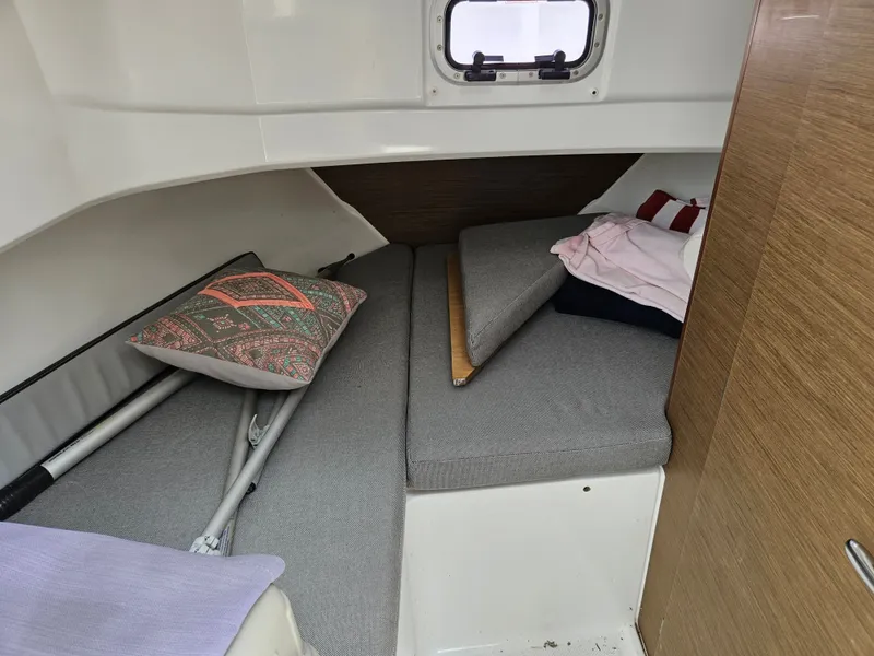 Slide: The Image of Interior of a Jeanneau NC 795 with gray cushions and pillows, window in the background. - 14