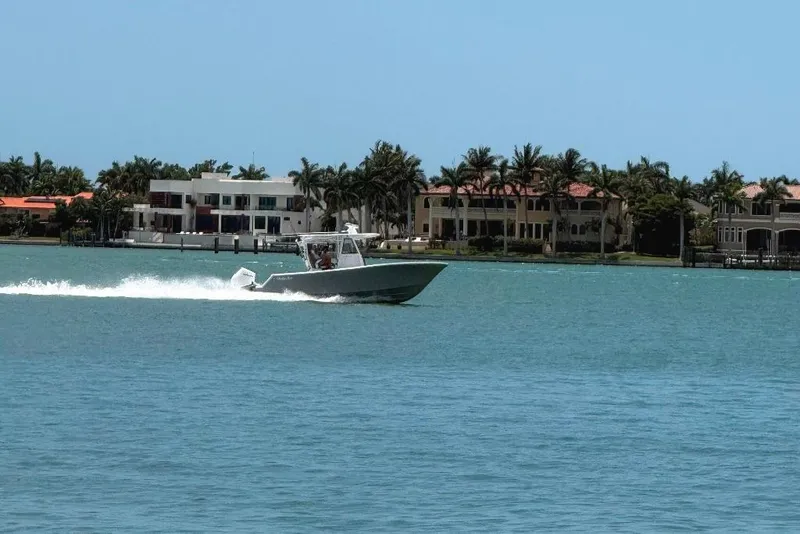 Slide: The Image of 2023 Onslow Bay 27 Offshore Edition cruising on a sunny waterfront with luxury homes. - 11