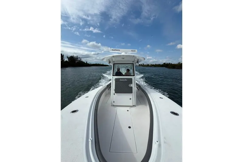 Slide: The Image of 2023 Onslow Bay 27 Offshore Edition boat cruising on a scenic waterway under a blue sky. - 4