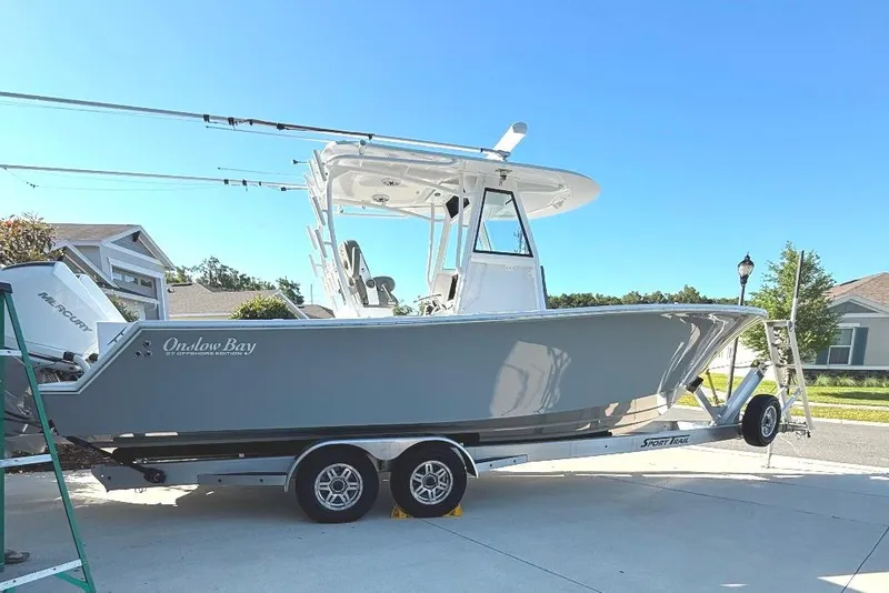 Slide: The Image of 2023 Onslow Bay 27 Offshore Edition boat on trailer, parked in residential area. - 2