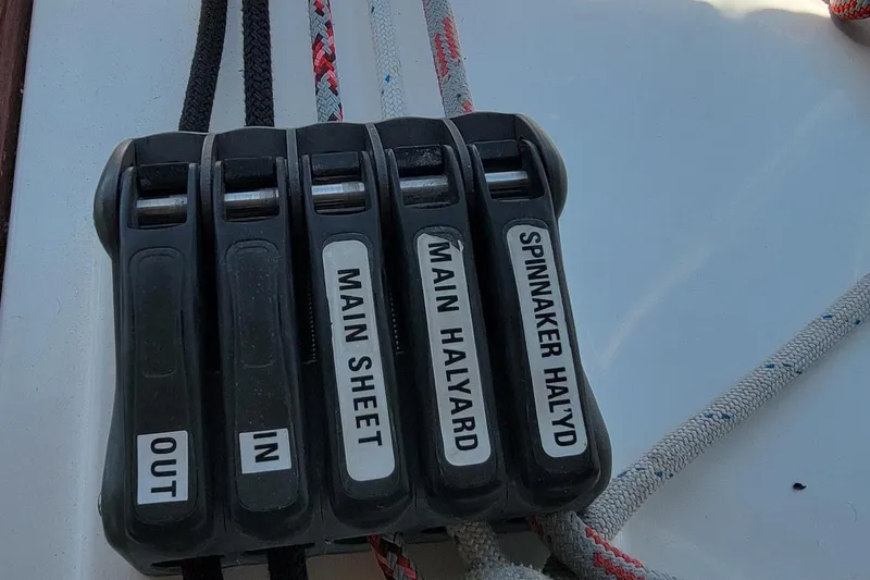 Slide: The Image of Close-up of rope clutches on a sailboat, labeled for various sail controls. - 29