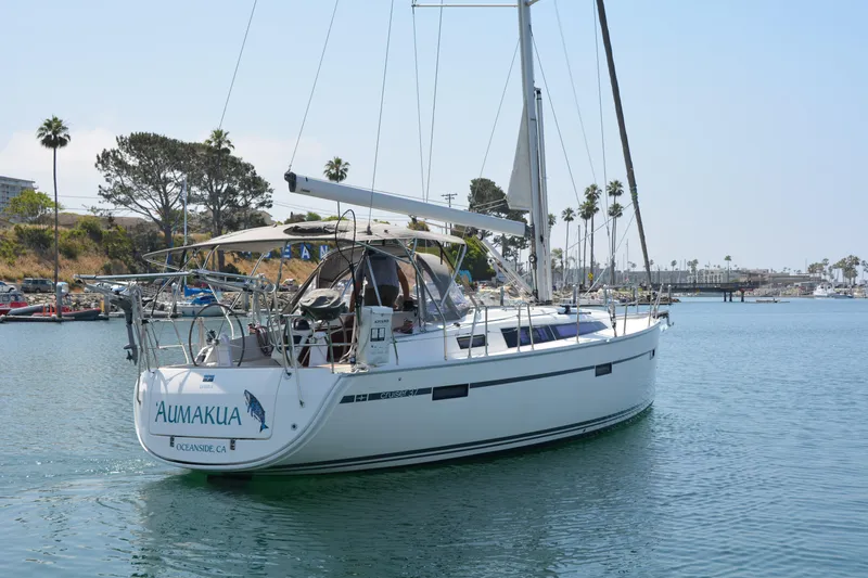 Slide: The Image of A 2014 Bavaria Cruiser 37 sails in a calm harbor with palm trees in the background. - 1