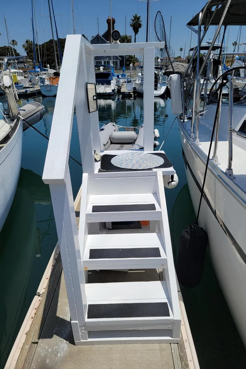 Slide: The Image of A white staircase leads to a dock between two sailboats in the marina. - 48