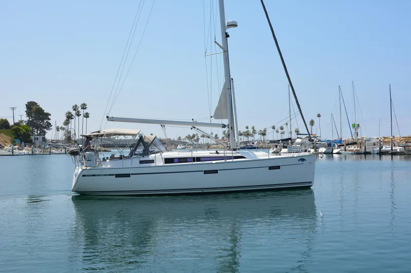 Slide: The Image of A white sailing yacht calmly docked in a harbor, surrounded by other boats and palm trees in the background. - 47