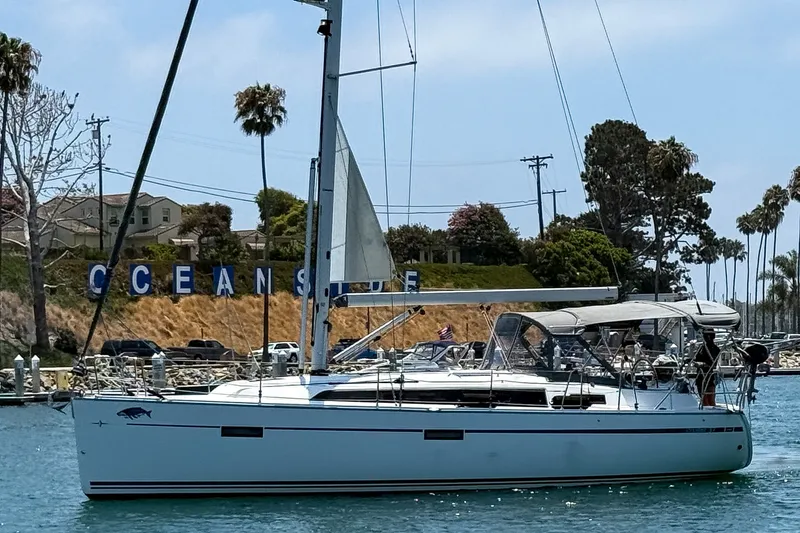 Slide: The Image of 2014 Bavaria Cruiser 37 sailboat in Oceanside harbor, surrounded by palm trees and clear skies. - 7