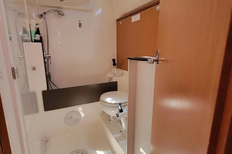 Slide: The Image of The image shows a boat bathroom with a shower, toilet, and wood paneling. - 18