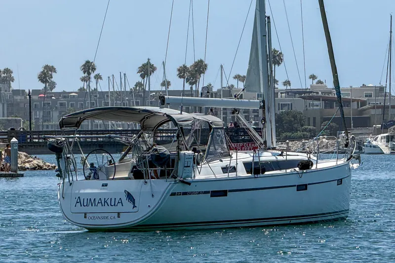 Slide: The Image of 2014 Bavaria Cruiser 37 sailboat named 'Aumakua' in a marina with palm trees. - 4