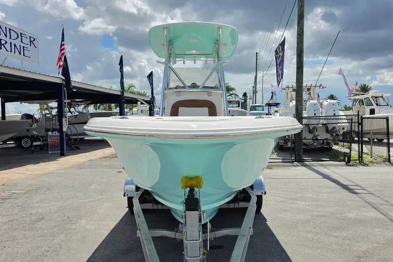 Slide: The Image of 2026 Pioneer 222 Sportfish boat on trailer at a marina under a cloudy sky. - 7