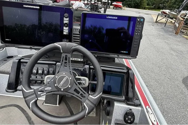 Slide: The Image of 2024 Triton 20XP Patriot boat dashboard with steering wheel and navigation screens. - 99