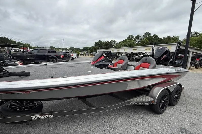 The Image of 2024 Triton 20XP Patriot boat on trailer, featuring sleek design and red-accented seats. - 0