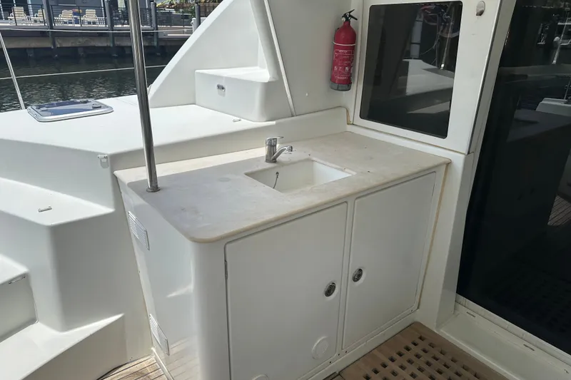 Slide: The Image of Outdoor sink area on a 2010 Lagoon 440 catamaran, featuring storage cabinets and a fire extinguisher. - 62