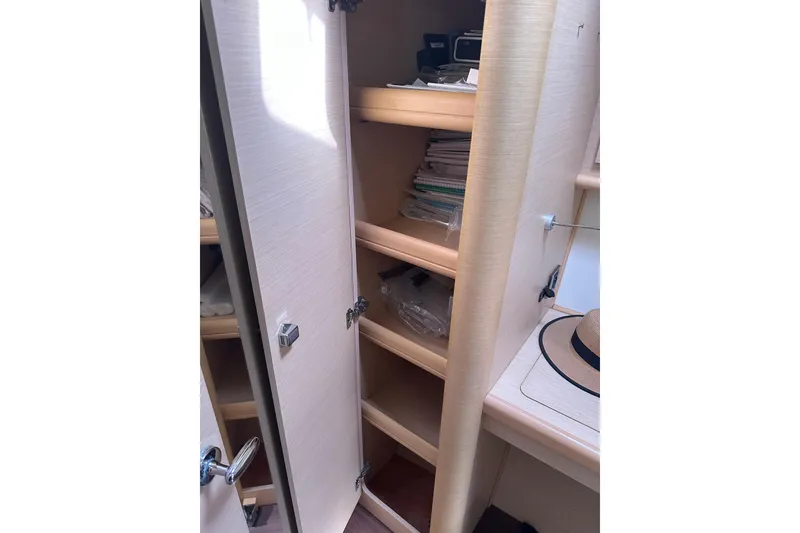Slide: The Image of Interior storage shelves on a 2010 Lagoon 440 yacht, featuring open cabinets and a hat. - 56