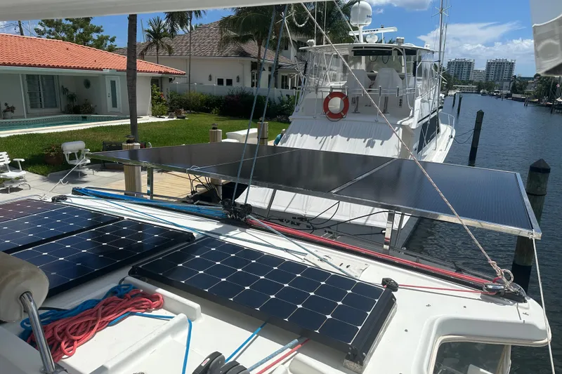 Slide: The Image of Catamaran Lagoon 440 (2010) with solar panels docked by waterfront homes. - 81