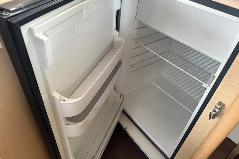Slide: The Image of Open refrigerator inside a 2010 Lagoon 440 yacht, showing empty shelves and door compartments. - 44