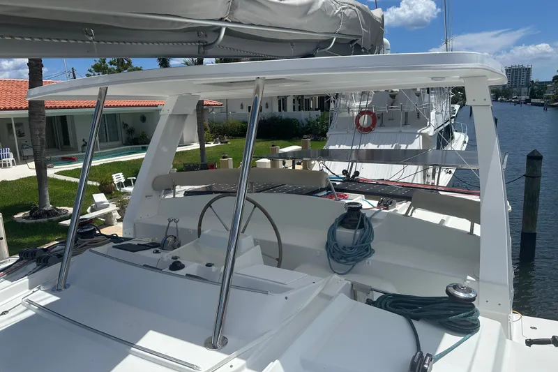 Slide: The Image of 2010 Lagoon 440 catamaran docked near waterfront homes, showcasing helm and deck area. - 78