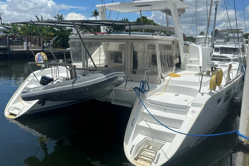 Slide: The Image of 2010 Lagoon 440 catamaran docked with inflatable tender, sunny marina setting. - 74