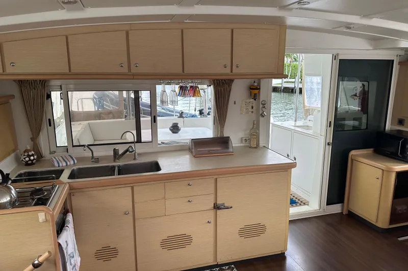 Slide: The Image of Interior of 2010 Lagoon 440 catamaran kitchen with wooden cabinets and waterfront view. - 40