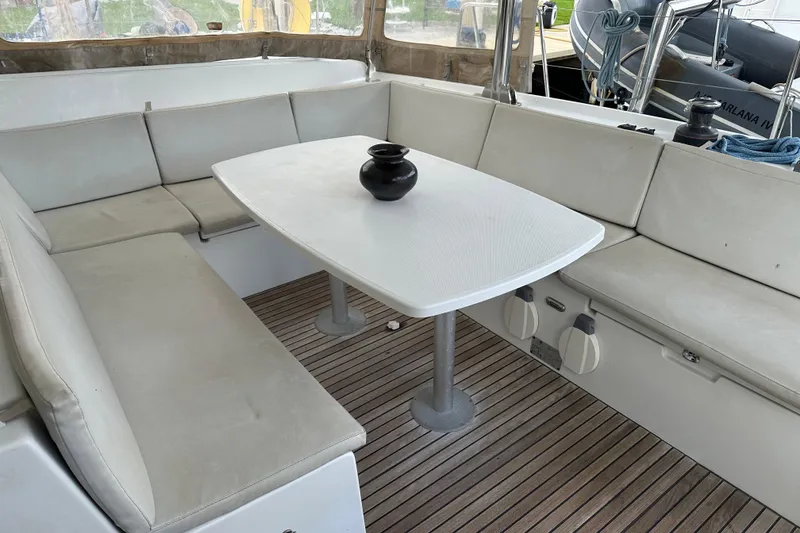 Slide: The Image of Spacious Lagoon 440 catamaran cockpit with white seating and table, featuring a black vase. - 64