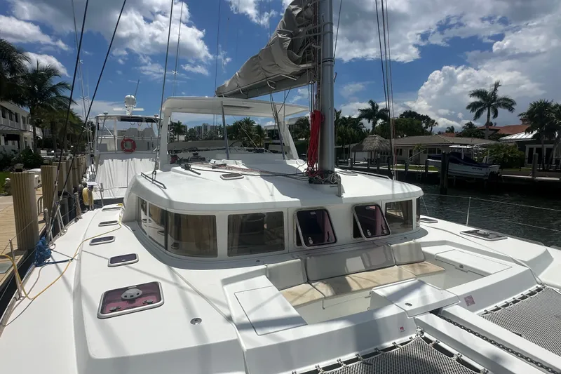 Slide: The Image of 2010 Lagoon 440 catamaran docked, featuring spacious deck and modern design under a sunny sky. - 76