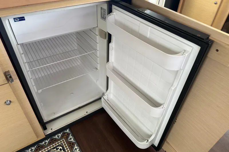 Slide: The Image of Open fridge inside a 2010 Lagoon 440 yacht, showcasing empty shelves and door compartments. - 43