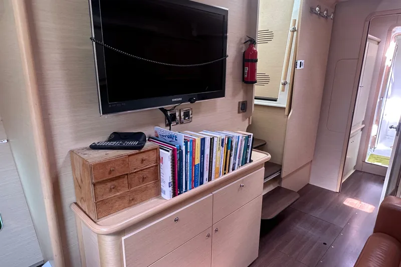Slide: The Image of Interior of a 2010 Lagoon 440 yacht with TV, books, and wooden drawers. - 49