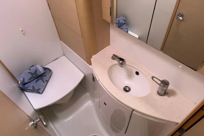 Slide: The Image of Compact bathroom in a 2010 Lagoon 440 yacht, featuring a sink and toilet with starfish towels. - 59