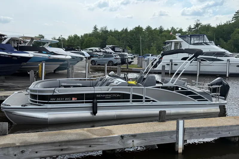The Image of 2023 Bennington 25RTSB pontoon boat docked at marina with other boats. - 0