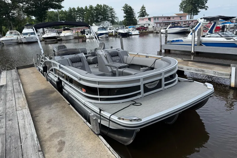 Slide: The Image of 2023 Bennington 25RTSB pontoon boat docked at a marina, featuring sleek design and spacious seating. - 1