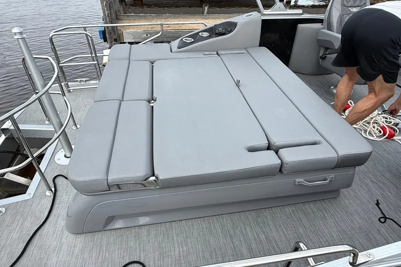 Slide: The Image of 2023 Bennington 25RTSB boat with gray cushioned seating and deck, docked by the water. - 10
