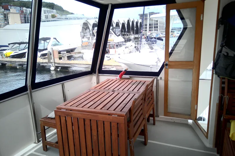 Slide: The Image of 1986 CHB Ponderosa yacht interior with wooden table, chairs, and marina view. - 18