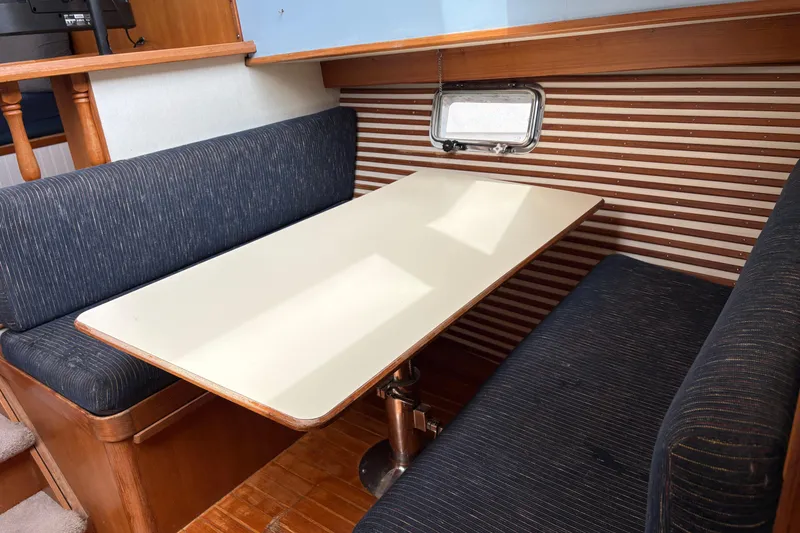 Slide: The Image of 1986 CHB Ponderosa boat interior with dining area, featuring a table and cushioned seating. - 31