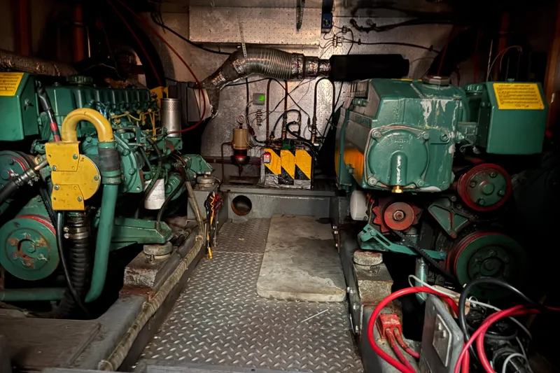 Slide: The Image of Engine room of a 1986 CHB Ponderosa boat, featuring dual green engines and mechanical components. - 41