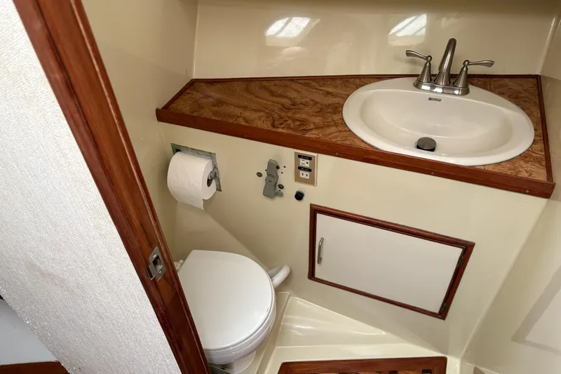 Slide: The Image of Compact 1986 CHB Ponderosa boat bathroom with sink, toilet, and wood accents. - 29