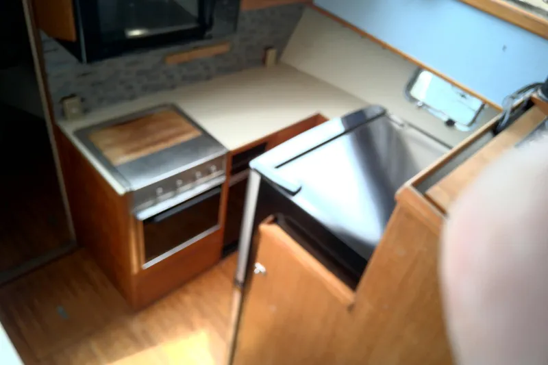 Slide: The Image of 1986 CHB Ponderosa yacht kitchen with stove, countertop, and wooden cabinetry. - 32