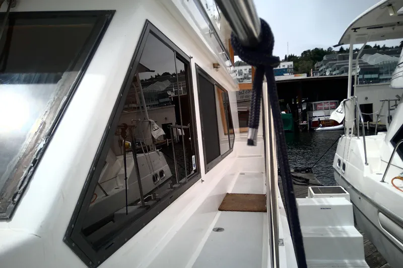 Slide: The Image of 1986 CHB Ponderosa boat docked, showcasing side view with windows and mooring line. - 6