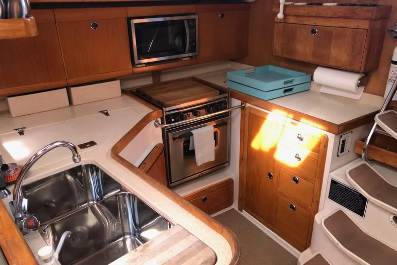 Slide: The Image of 1999 Catalina 400 yacht kitchen with wooden cabinetry, stainless steel sink, and built-in appliances. - 7