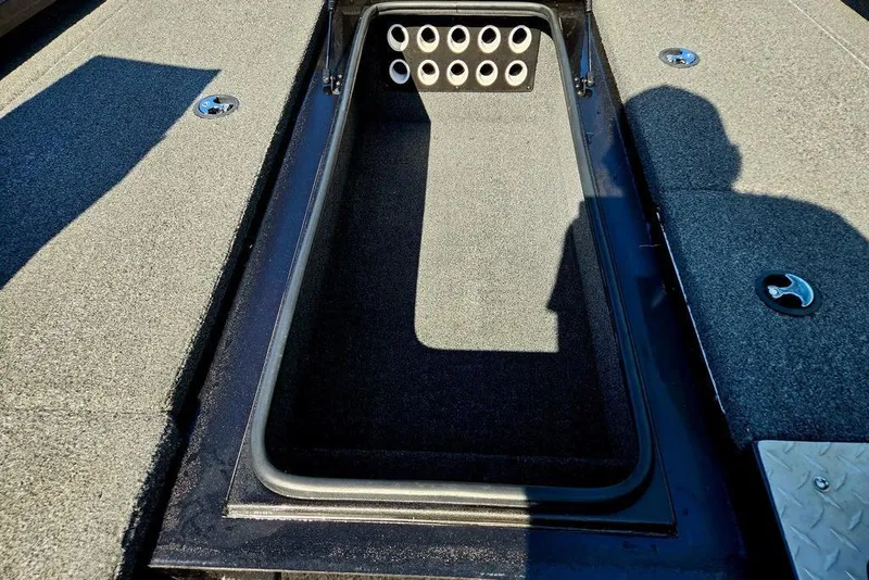 Slide: The Image of 2022 Vexus AVX1980 boat storage compartment with rod holders, carpeted interior. - 24