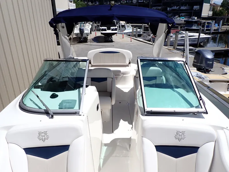 Slide: The Image of 2011 Chaparral 287 SSX boat with open cockpit, white seating, and blue canopy at marina. - 8