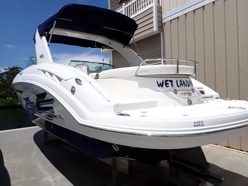 Slide: The Image of 2011 Chaparral 287 SSX boat with blue canopy docked near a building. - 1
