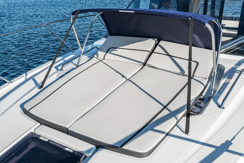 Slide: The Image of 2024 Bavaria R40 yacht with sunbed and canopy on deck, overlooking blue water. - 19