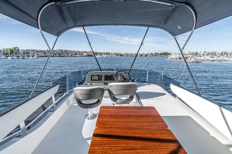 Slide: The Image of 2024 Bavaria R40 yacht helm with dual seats, wooden table, and canopy on open water. - 24