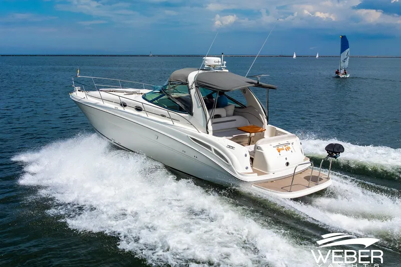 Slide: The Image of A 2005 Sea Ray 360 Sundancer cruising swiftly on the water, with a sailboat in the background. - 45