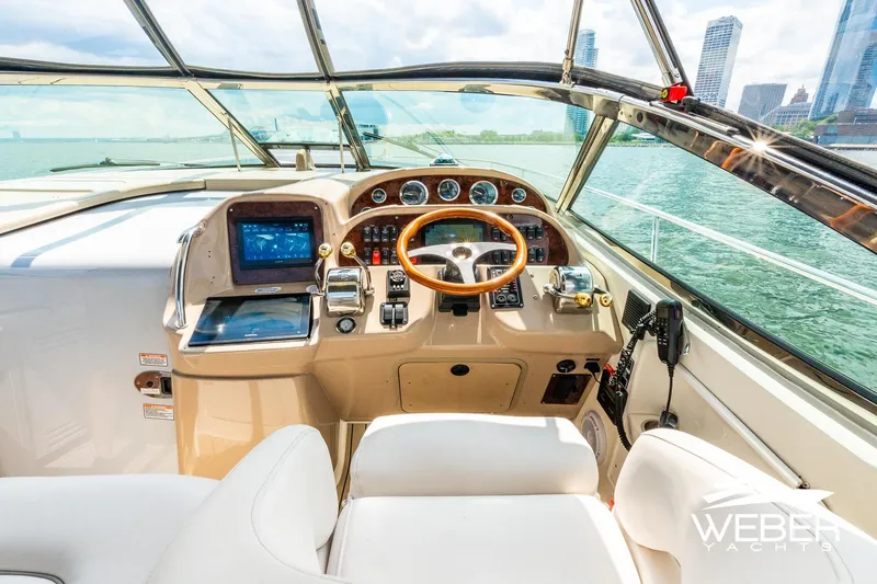 Slide: The Image of The cockpit of a 2005 Sea Ray 360 Sundancer with a sleek wooden steering wheel and modern instruments. - 7