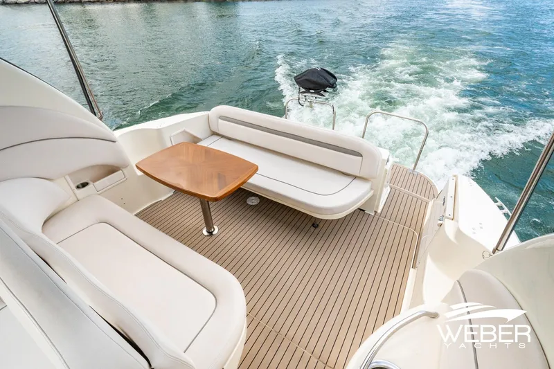 Slide: The Image of The image shows the aft deck of a 2005 Sea Ray 360 Sundancer with beige seating and a wooden table. - 14