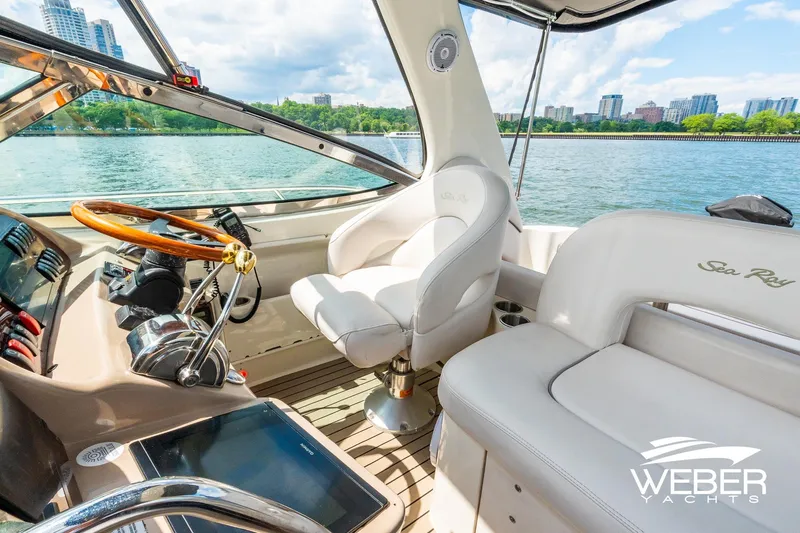Slide: The Image of The image shows the cockpit of a 2005 Sea Ray 360 Sundancer with luxurious seating and a wooden steering wheel. A cityscape is visible in the background. - 12