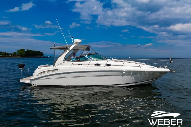 Slide: The Image of A 2005 Sea Ray 360 Sundancer on the water, with blue sky and shoreline in the background. - 38