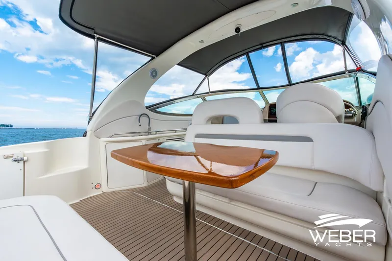 Slide: The Image of The image shows the cockpit of a 2005 Sea Ray 360 Sundancer with sleek white seating and a wooden table. - 21