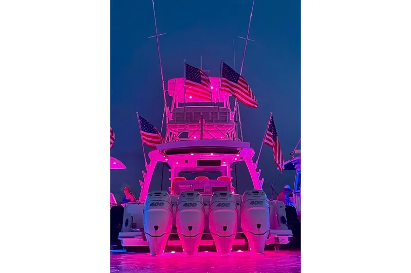 Slide: The Image of 2017 Boston Whaler 420 Outrage illuminated in pink with American flags at night. - 41