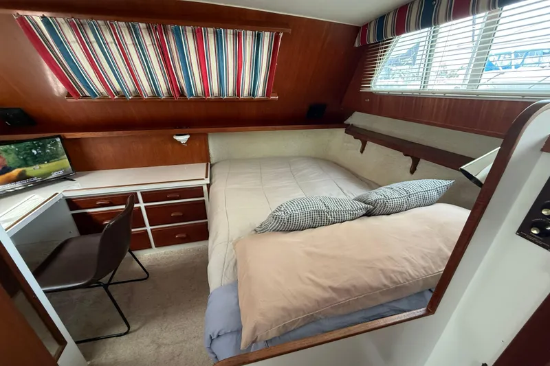 Slide: The Image of 1985 Tollycraft 34 Sundeck Motor Yacht cabin with bed, desk, and striped curtains. - 31
